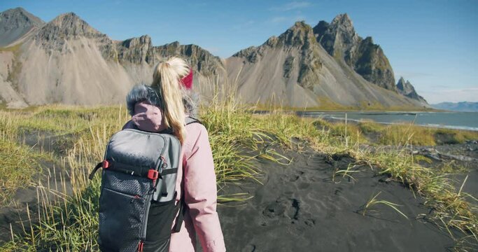 Morning scene of female traveler exploring Stokksnes cape with Vestrahorn (Batman Mountain) on background. Sunny summer day in Iceland
