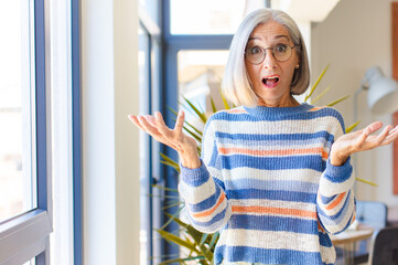 middle age woman feeling extremely shocked and surprised, anxious and panicking, with a stressed...