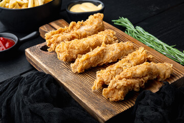 Crispy chicken tenders on black wooden background