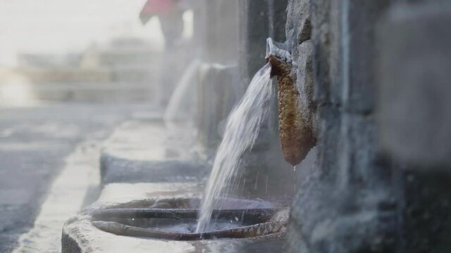 stone hot springs pouring boiling water. burgas of orense. blur stone background. water jet with silk effect and steam