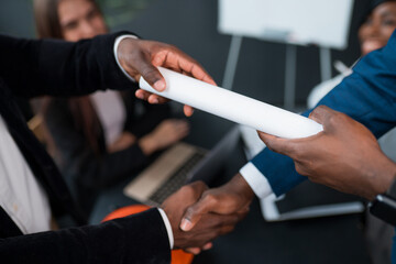 Obraz premium Close-up of a handshake of two African American men. The investor signed the contract and hands it over to the business partner