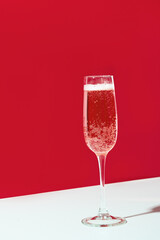 Wineglass of champagne on red and white creative background. Holiday celebration concept. Christmas holiday.