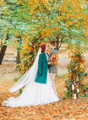 Fototapeta premium Wedding ceremony in the autumn park. The newlyweds standing near the decorated arch.