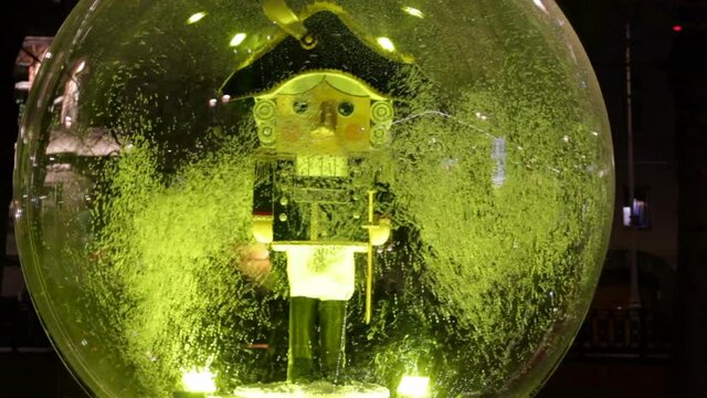 Giant snow globe with Nutcracker statue.Street decorated for New Year and Christmas holidays.Wood made doll soldier vintage handcraft puppet