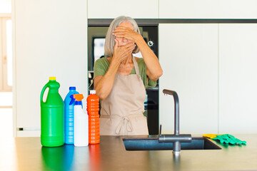 middle age woman covering face with both hands saying no to the camera! refusing pictures or...