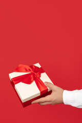 Close-up image of man hands holding gift box over red background. Christmas and New Year concept.