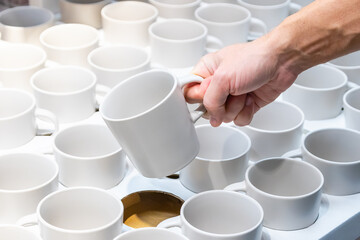 a man's hand selects a mug