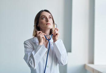 Woman with professional stethoscope Doctor in medical gown in bright room