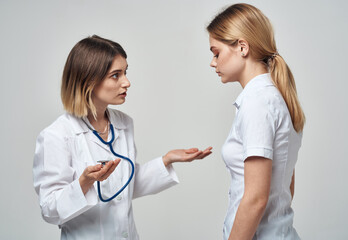 A nurse with a stethoscope and a patient on a light background