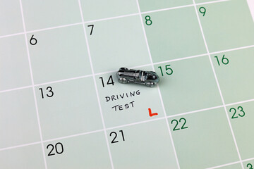 A small chrome model car on a calendar indicating a driving test.