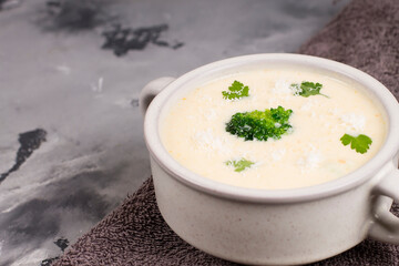 Cheese soup with herbs, in a plate, on a gray background, top view