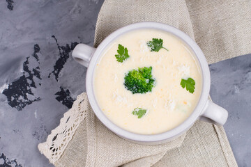 Cheese soup with herbs, in a plate, top view