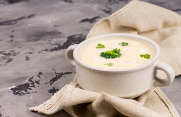 Cheese soup with herbs, in a plate, on a gray background, top view