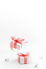 Christmas gift. White gift box with red ribbon, New Year balls in xmas composition on white background for greeting card. Winter festive composition with copy space.