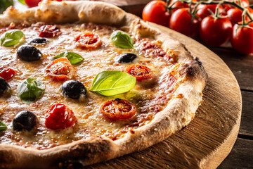 Homemade pizza with tomatoes mozzarella cheese olives and basil