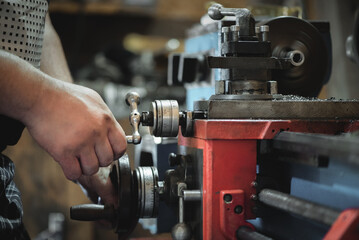 Worker is working on the lathe machine close up.