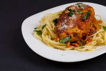 Chicken parmigiana on a white plate with spaghetti