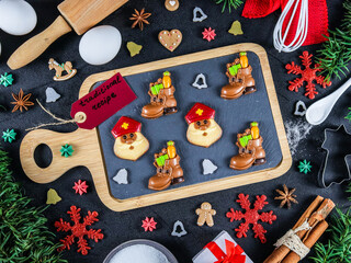 christmas card with cookies.

Chocolate chip cookies on a wooden board, and around the ingredients and decor Christmas, top view close-up.