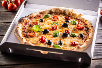 Pizza in a cardboard box on table ready to customer.