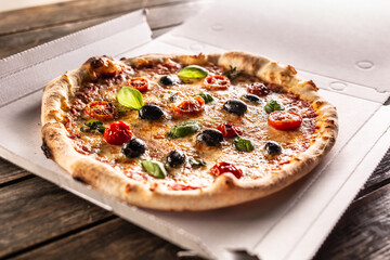 Pizza in a cardboard box on table ready to customer.