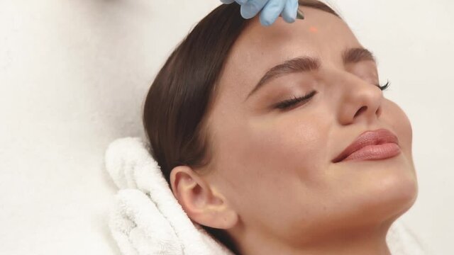 cosmetologist arm using erbium laser on woman face