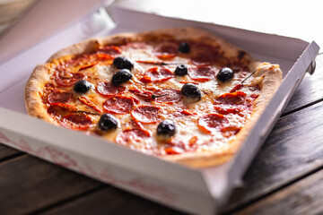 Pizza in a cardboard box on table ready to customer.
