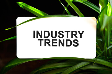 INDUSTRY TRENDS text on white surrounded by green leaves