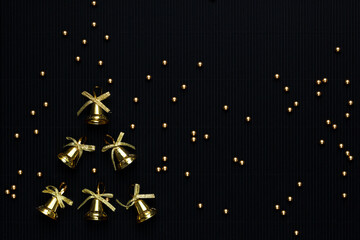Gold bells and gold balls on a black background. Festive background. Christmas background. Background for the New Year's postcard. Festive postcard. Stylish congratulations concept. Free place.