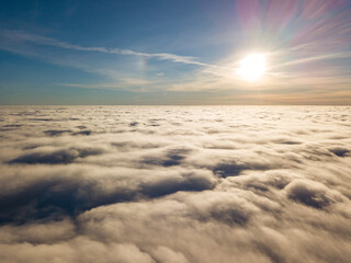 Aerial high flight over curly clouds. The sun's rays shine on the clouds.