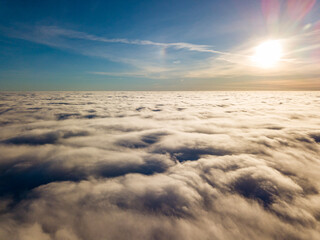 Fototapeta na wymiar Aerial high flight over curly clouds. The sun's rays shine on the clouds.