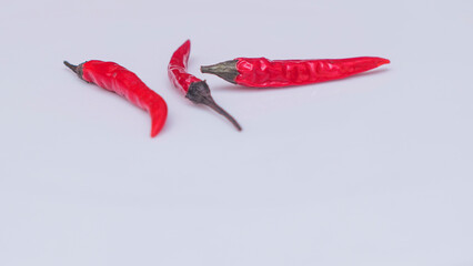 Three bright red chili peppers on white background. Space for text. Design concept.