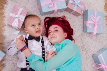 Children with gifts are lying on the floor, a boy with Down syndrome with soestroy, a new mood,...