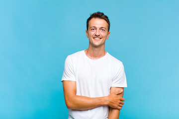 young handsome man laughing shyly and cheerfully, with a friendly and positive but insecure attitude