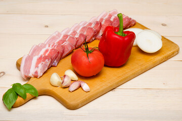 vegetables and raw meat chopped bacon on wooden board
