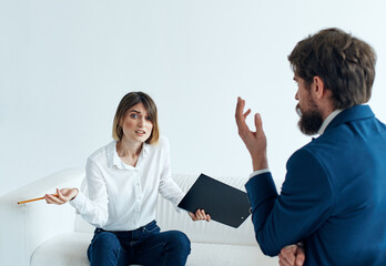 Business man in a classic suit and a woman on the couch with documents in the hands of a psychologist working