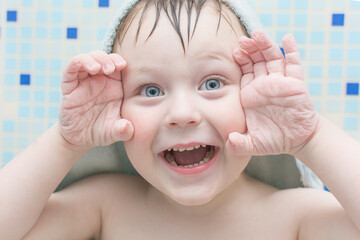 after a shower, the blue-eyed boy grimaced and showed clean wrinkled palms. Horizontal photo,...