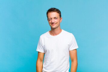 young handsome man looking happy and friendly, smiling and winking an eye at you with a positive...