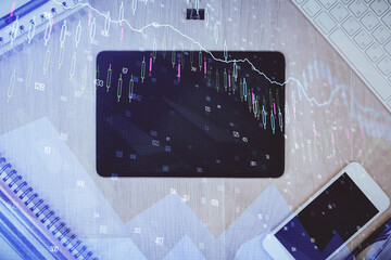 Double exposure of forex graph hologram over desktop with phone. Top view. Mobile trade platform concept.