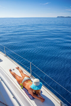 Young woman in bathing suit is sunbathing on yacht in the sea