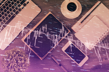 Double exposure of forex chart hologram over desktop with phone. Top view. Mobile trade platform concept.