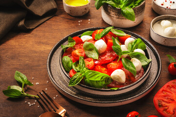 Caprese - italian salad with red tomatoes and mozzarella cheese with green basil leaves. Top view, wooden table