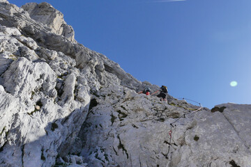 Two people climbing rocks on a via ferrata on a sunny summer day