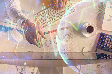 Multi exposure of man's hands typing over computer keyboard and forex graph hologram drawing. Top view. Financial markets concept.
