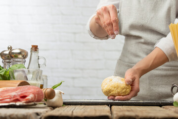 Professional chef in white uniform pours some flour on the dough for cooking pasta alla carbonara. Backstage of preparing traditional italian dish on white background. Frozen motion.