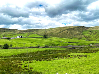 Fototapeta na wymiar High on the moors, with a white farmhouse in the distance in, Cliviger, Todmorden, UK