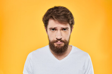 Obraz premium Man in white t-shirt emotions studio gestures with hands displeased facial expression yellow background