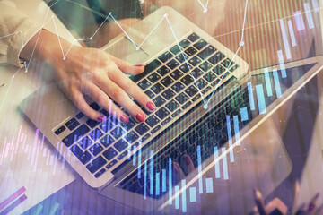 Double exposure of woman hands typing on computer and financial graph hologram drawing. Stock market analysis concept.