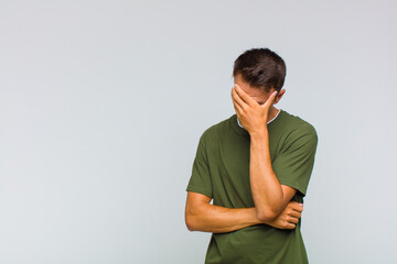young handsome man looking stressed, ashamed or upset, with a headache, covering face with hand