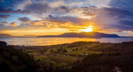 Panoramic Aerial Sunset View of an Island In the Pacific Northwest. Dramatic clouds highlight this drone shot of surrounding islands in the Salish Sea area of western Washington state. Lummi Island.