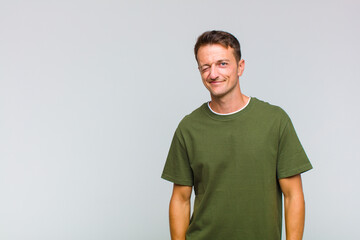 young handsome man looking happy and friendly, smiling and winking an eye at you with a positive...